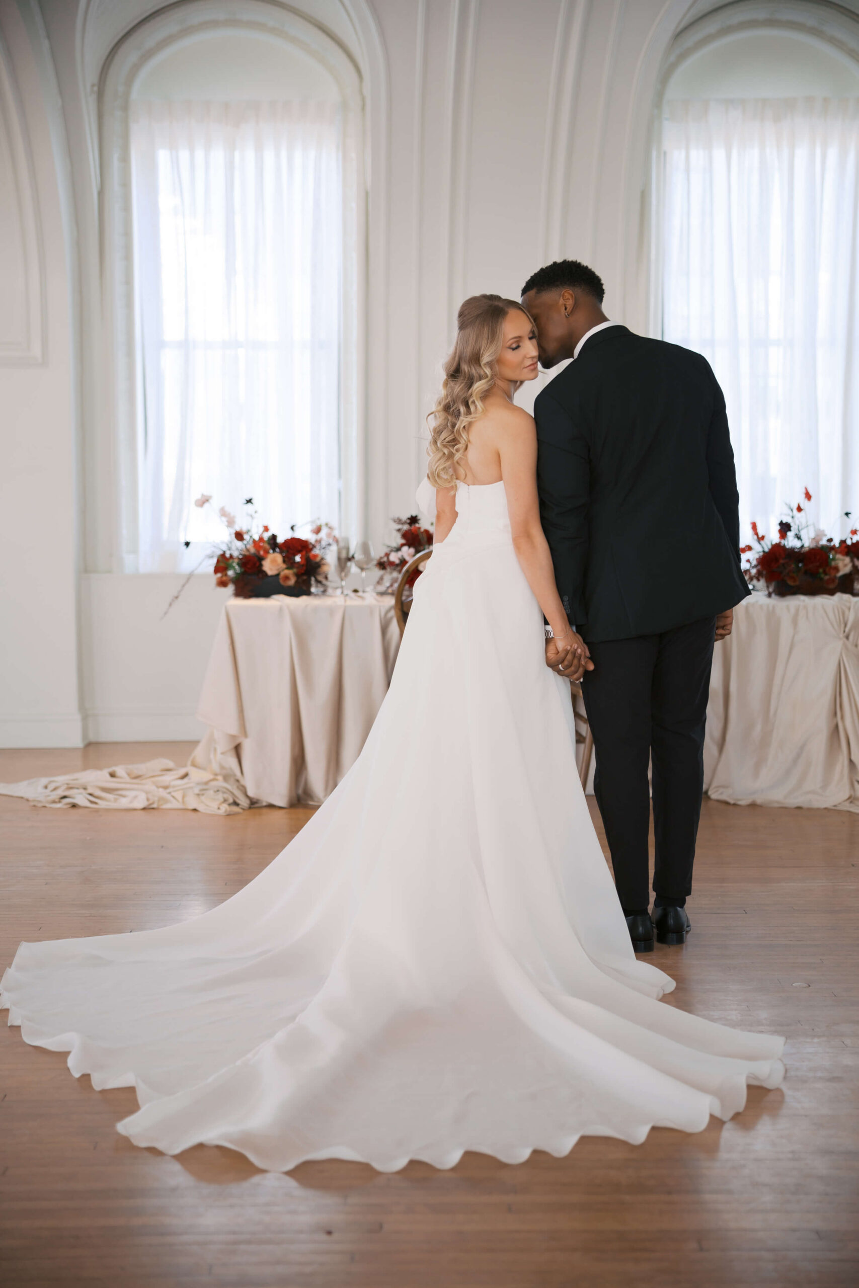 Newlyweds hold hands and stand with the train spread in their cottonwood hotel wedding reception space