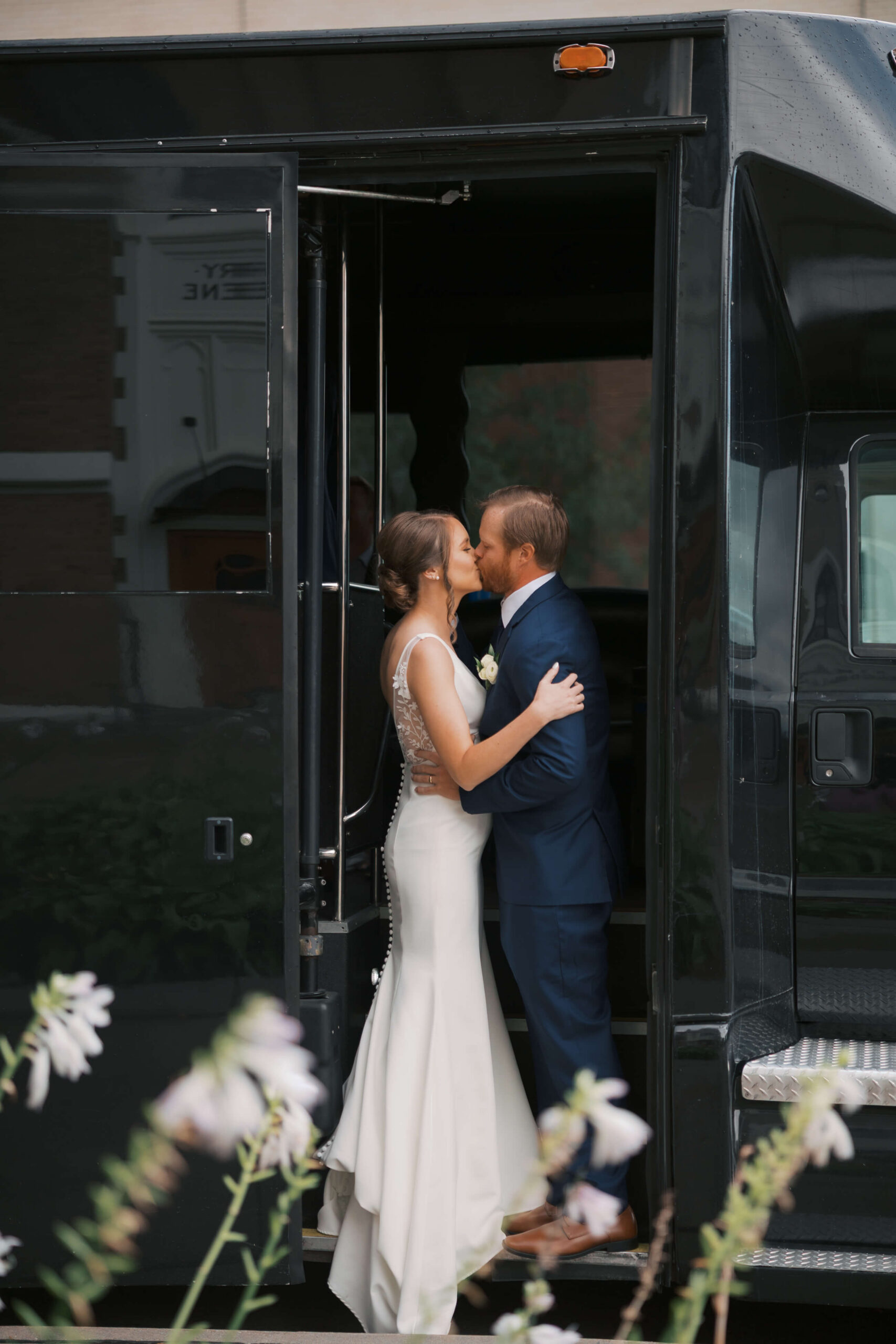 Newlyweds kiss on the entrance to a tour bus