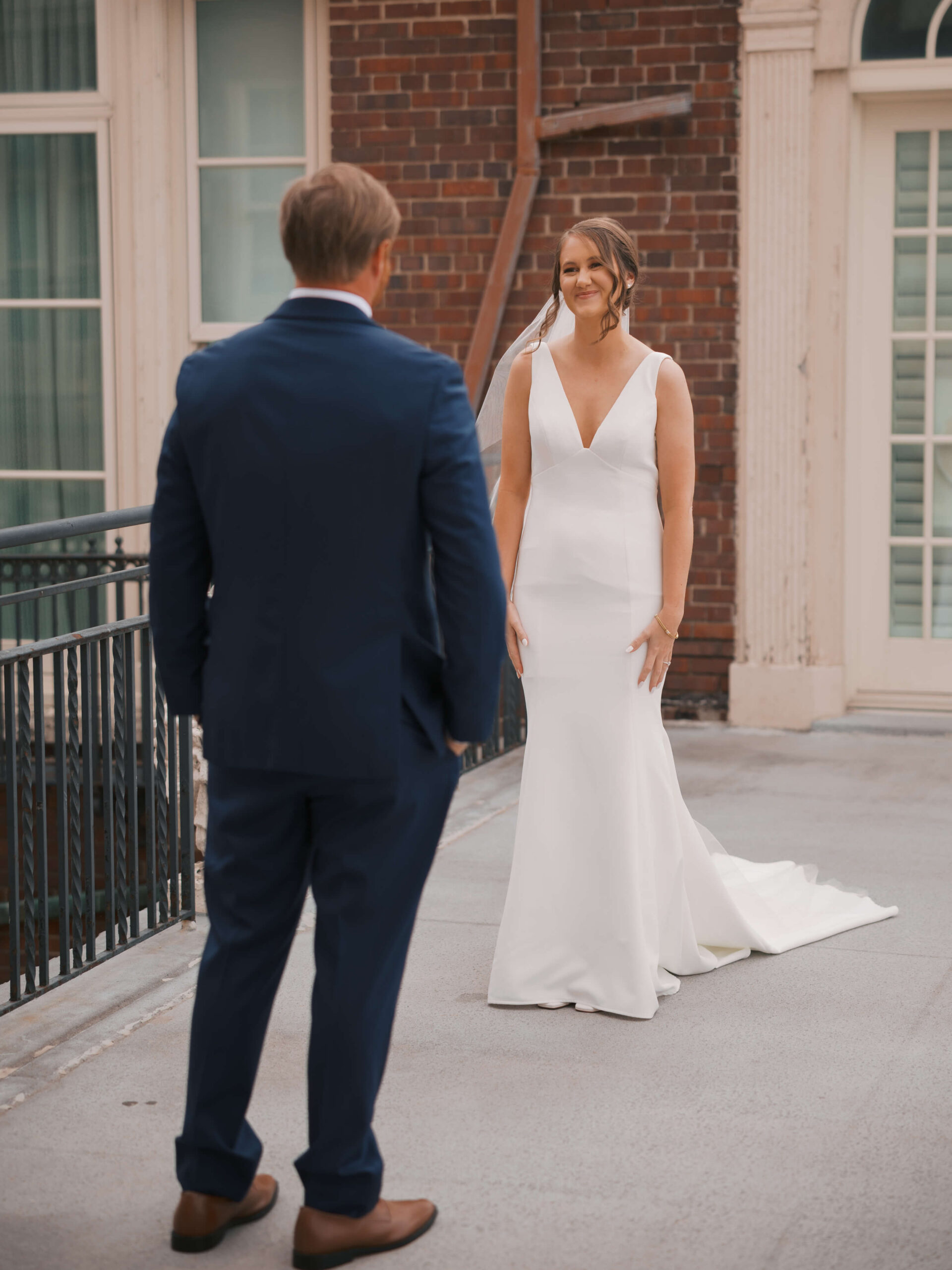 A bride smiles big during her first look with her groom during their magnolia hotel wedding