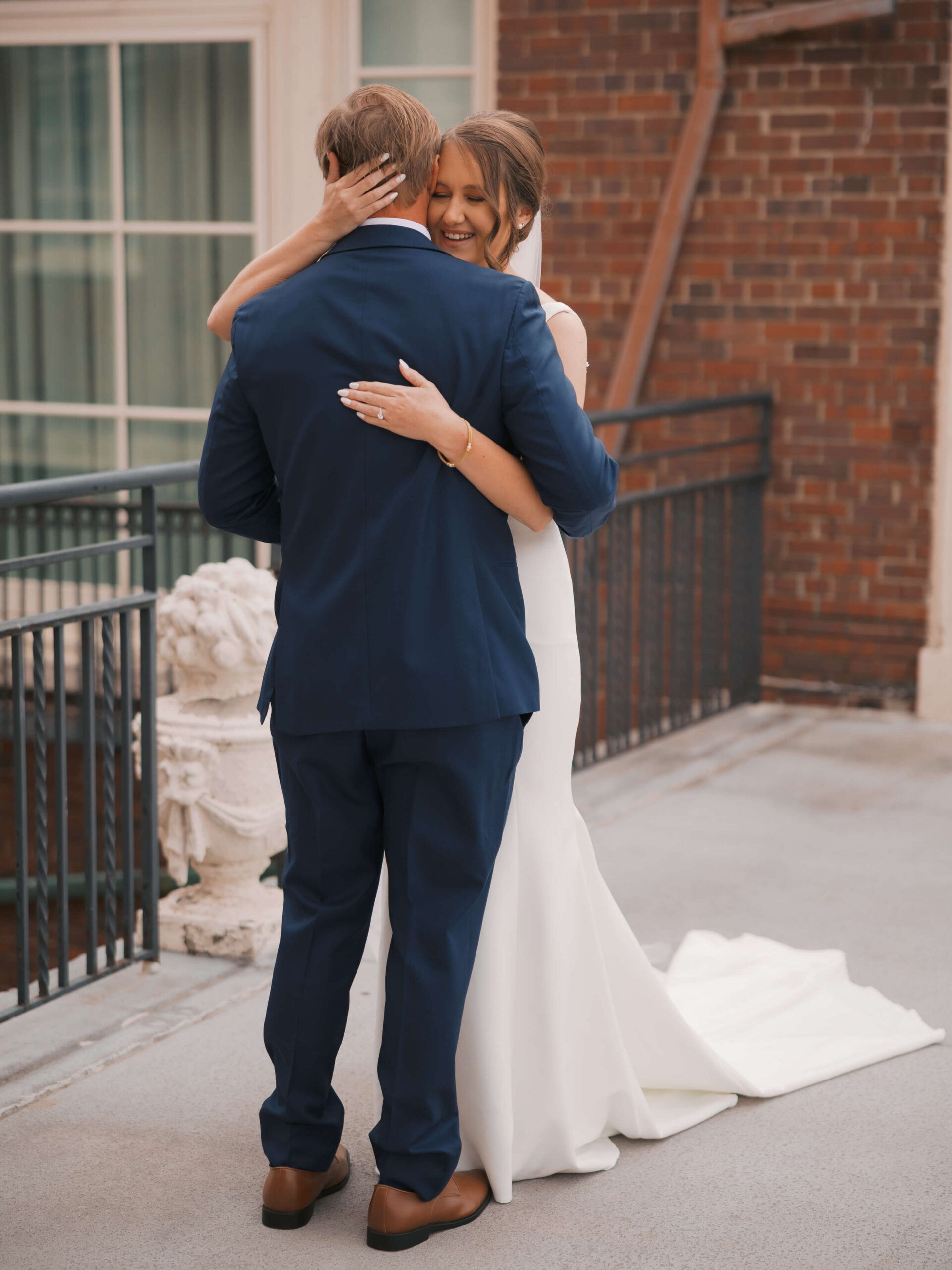 Newlyweds dance and smile on a balcony during their magnolia hotel wedding