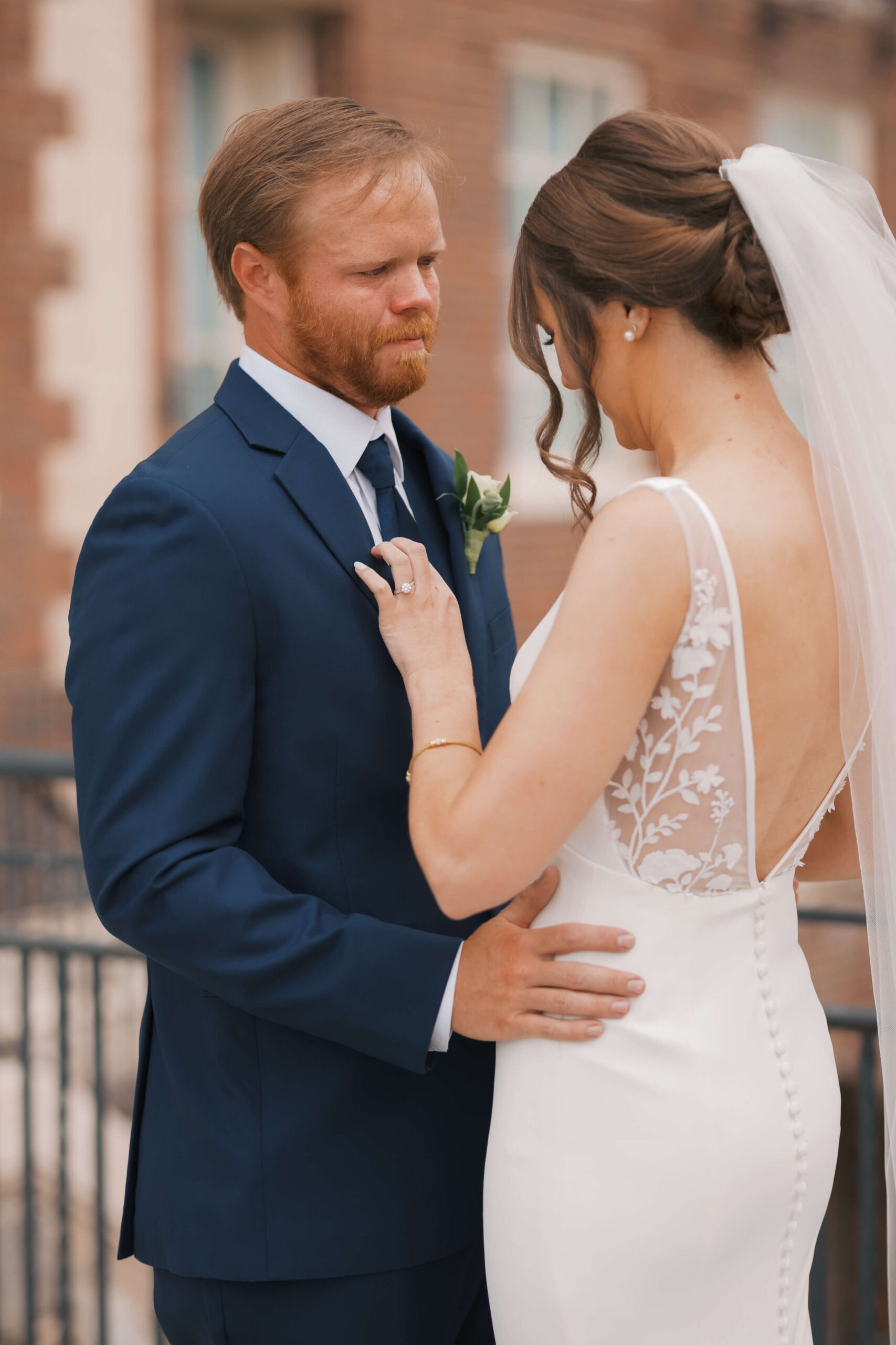 A groom holds back tears during his first look on a balcony with his bride before their magnolia hotel wedding