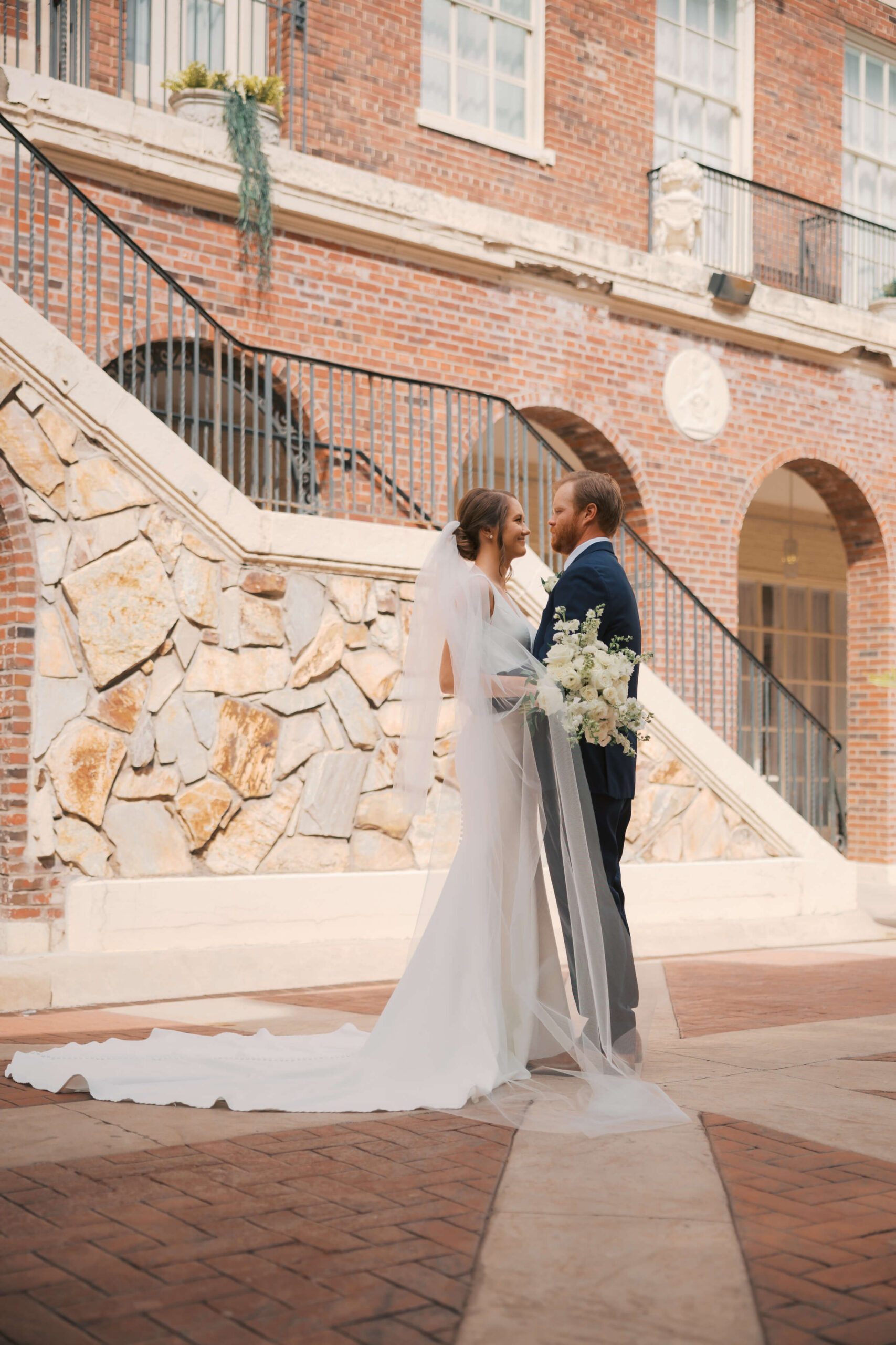 Newlyweds cuddle in a patio smiling at teach other during their magnolia hotel wedding