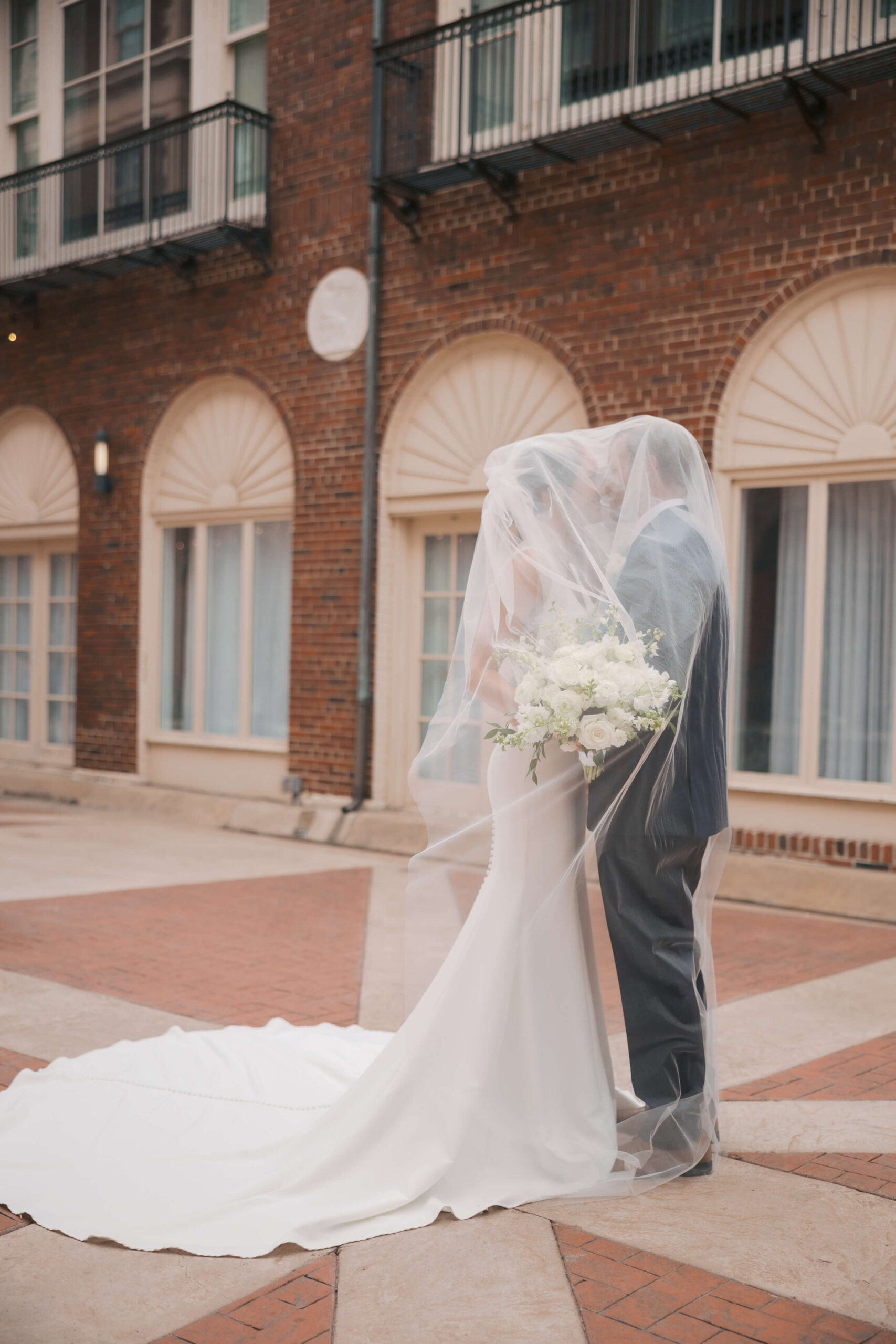 Newlyweds kiss while hiding under the veil in a patio