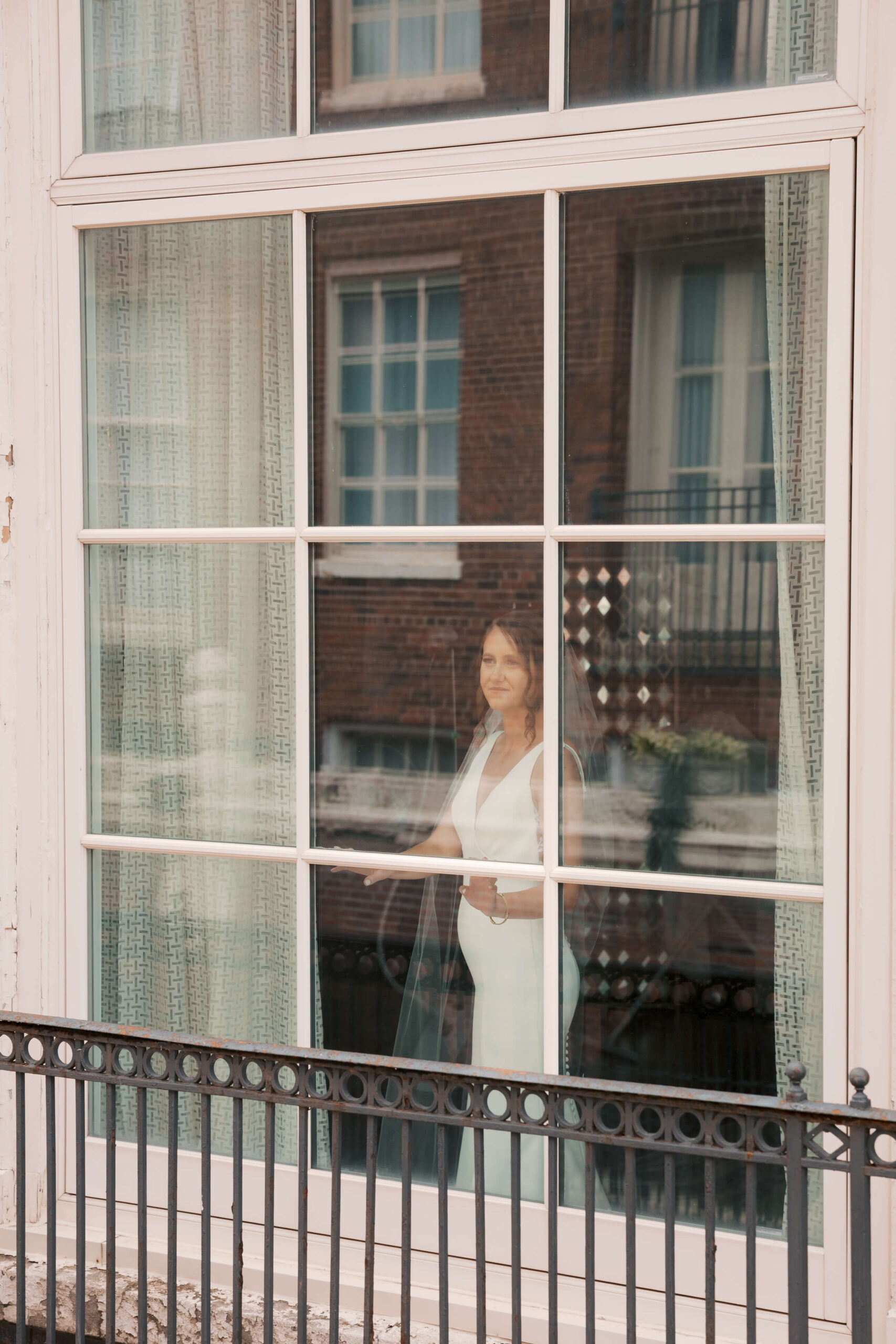 A look into a window as a bride stands in it gazing out