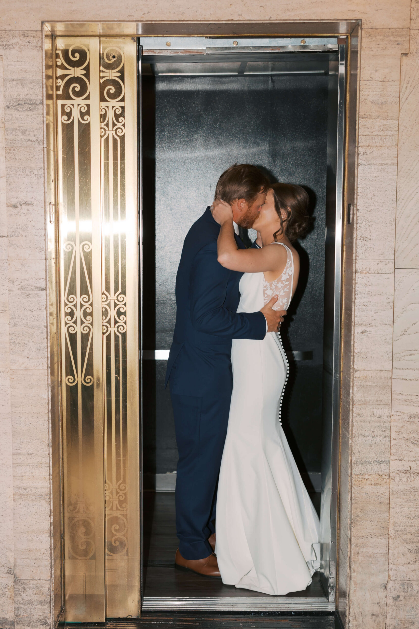 Newlyweds kiss in the ornate gold elevator