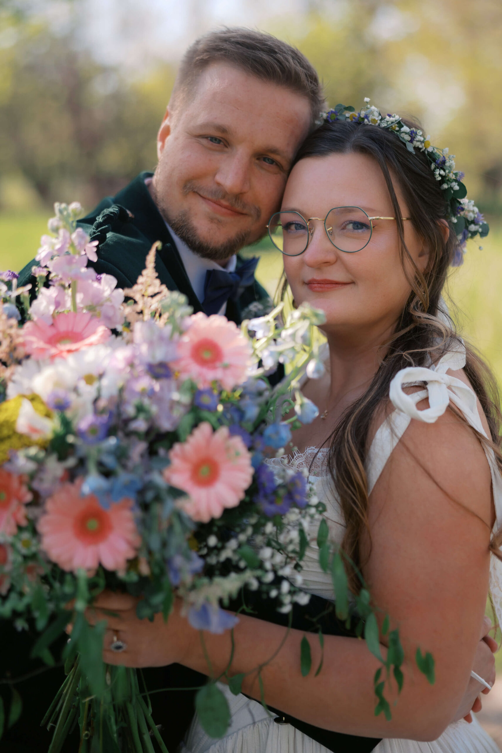 Newlyweds snuggle close while holding up the large colorful bouquet in a meadow at the northern lights venue