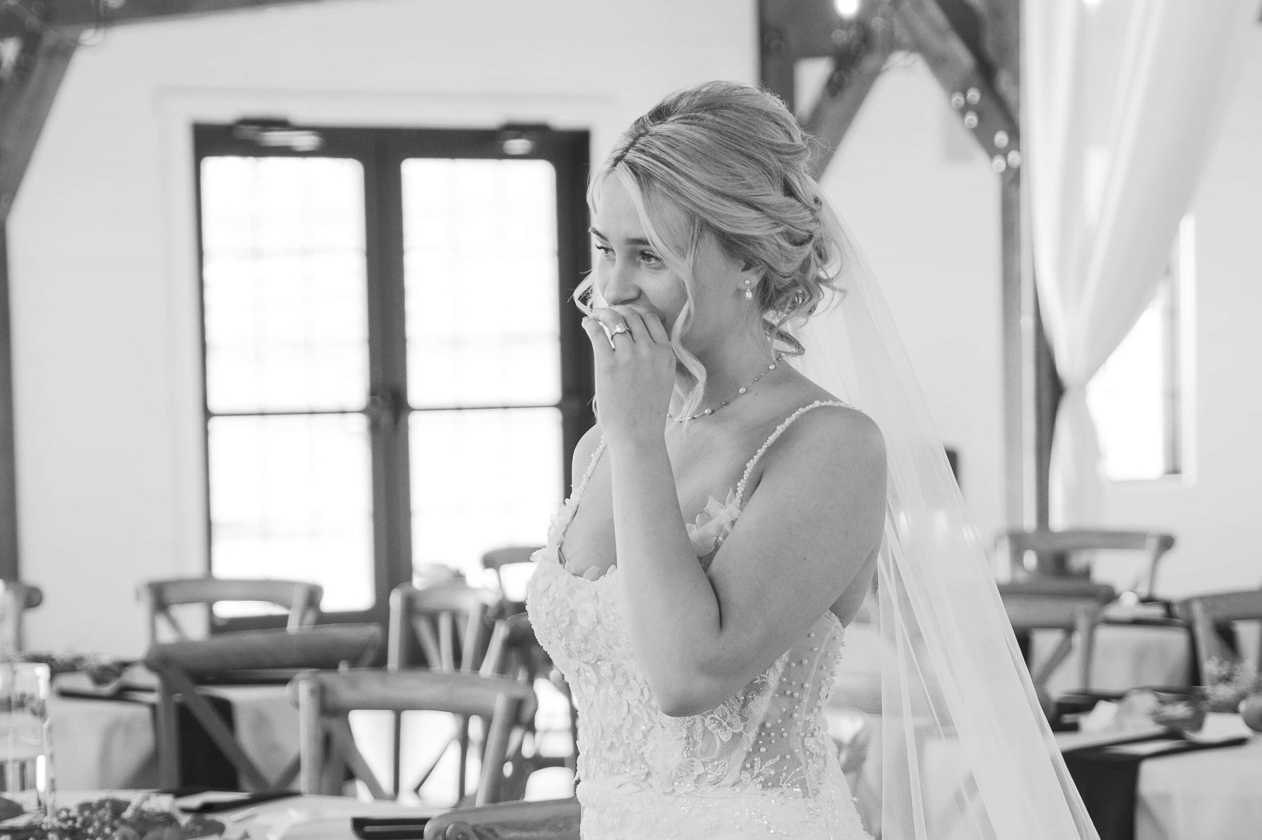A bride smiles while walking in her reception space in black and white at the Seven Willows wedding venue