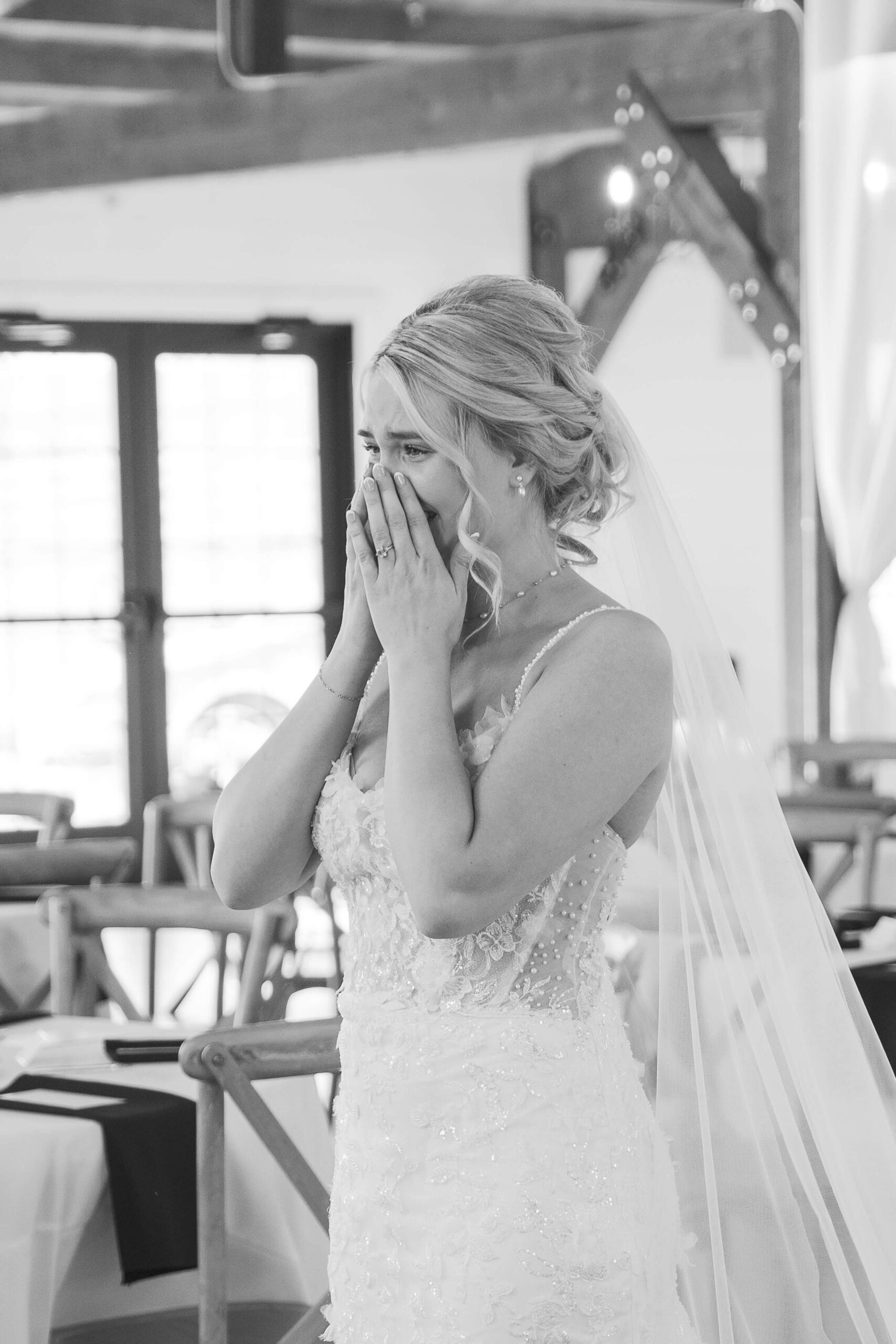 A bride cries in black and white with hands over her face at the Seven Willows wedding venue