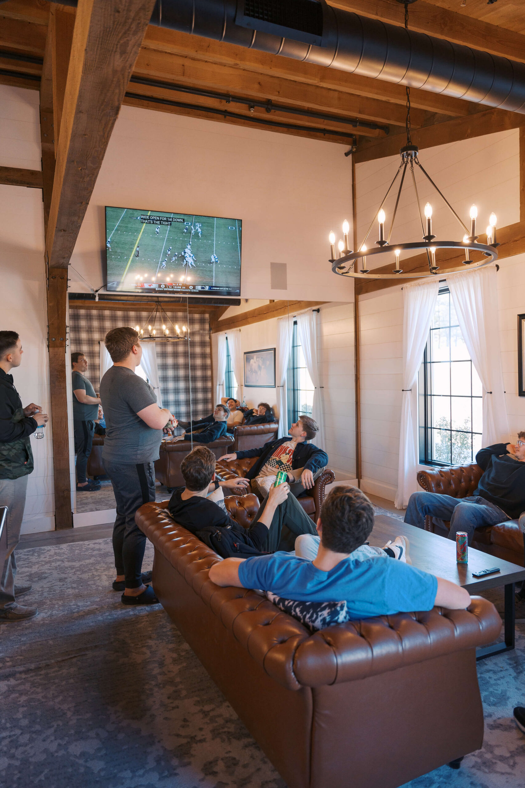 A look at a lively Seven Willows wedding venue groom's room watching football with leather couches