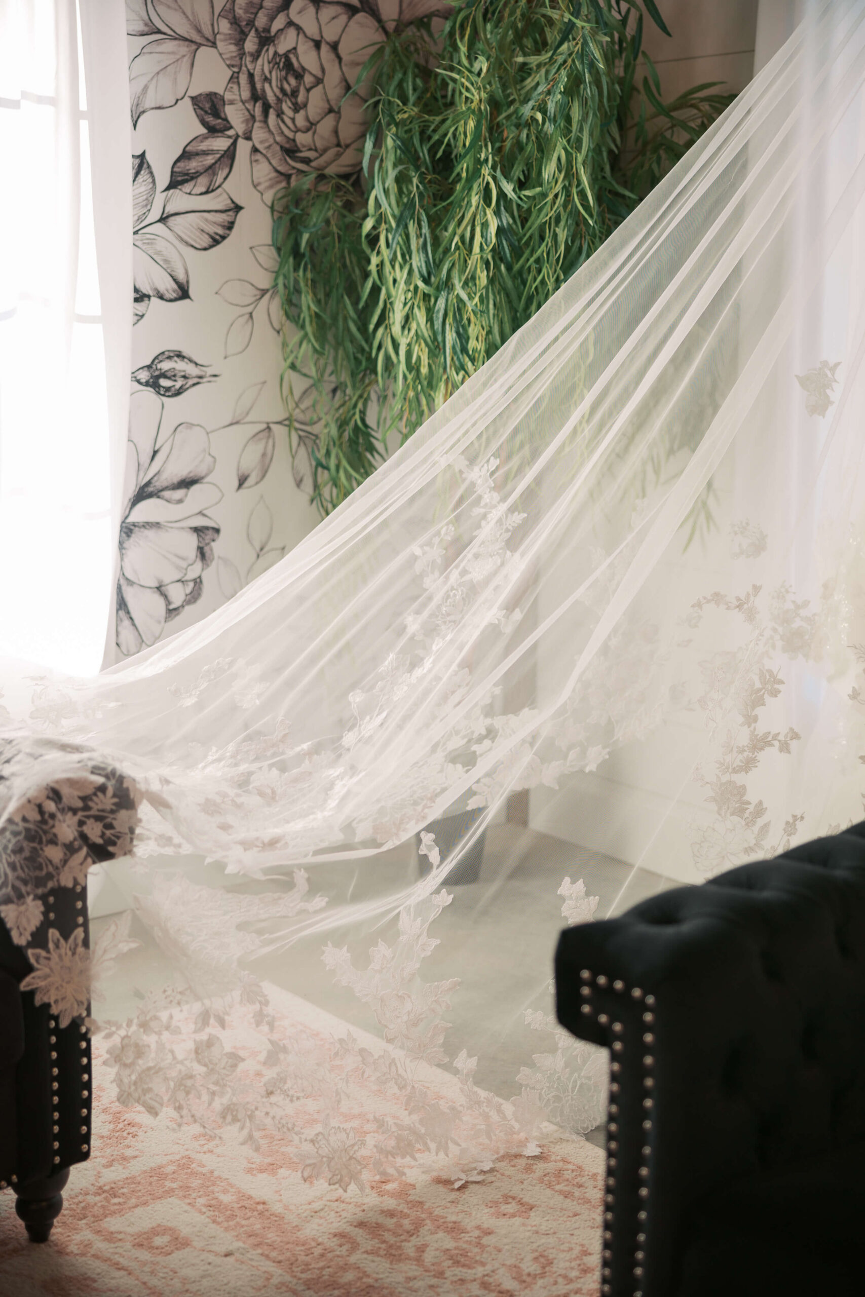 Details of a lace embroidered veil draped from a window to a couch