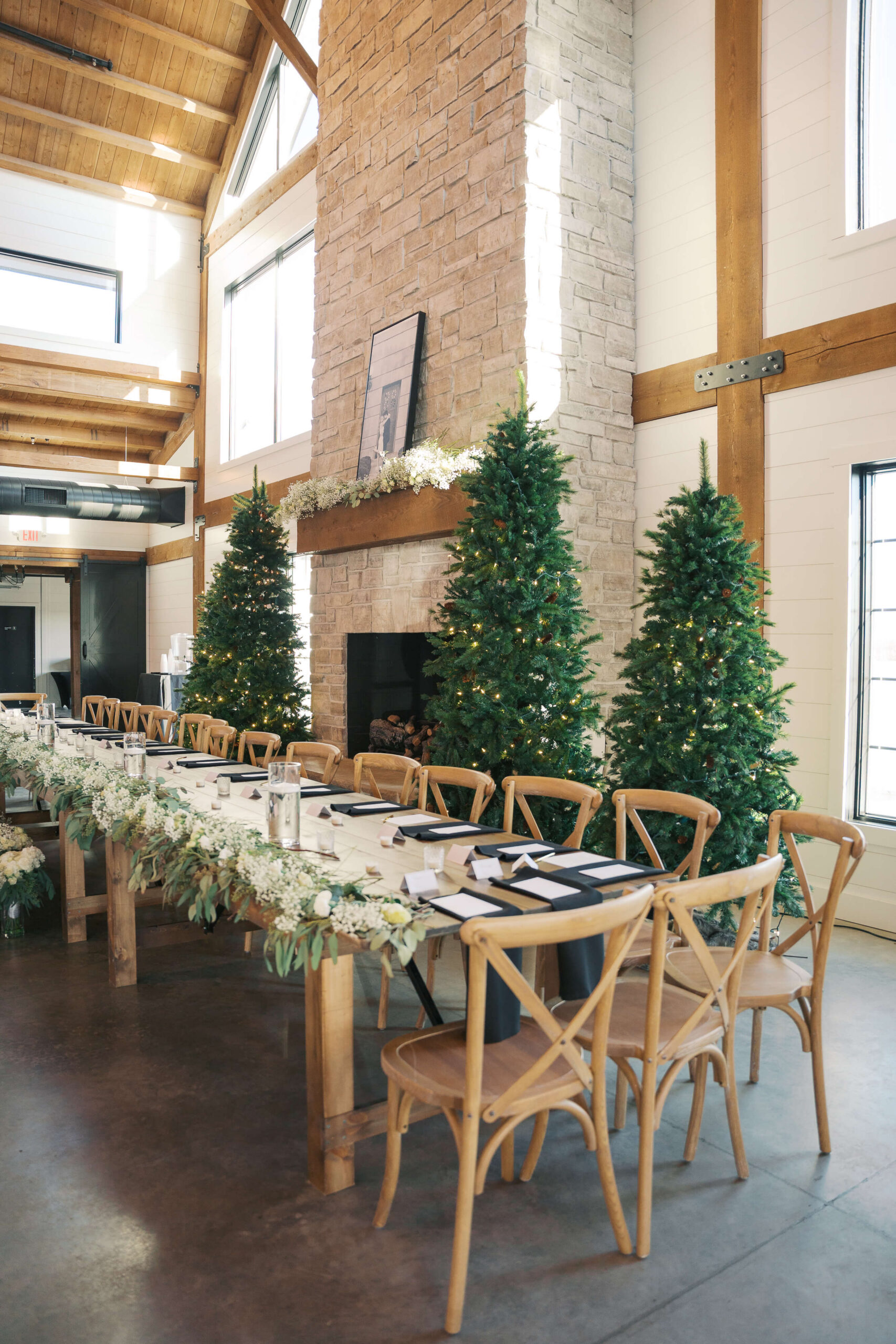 Details of a long wedding reception table in front of fireplace and christmas trees