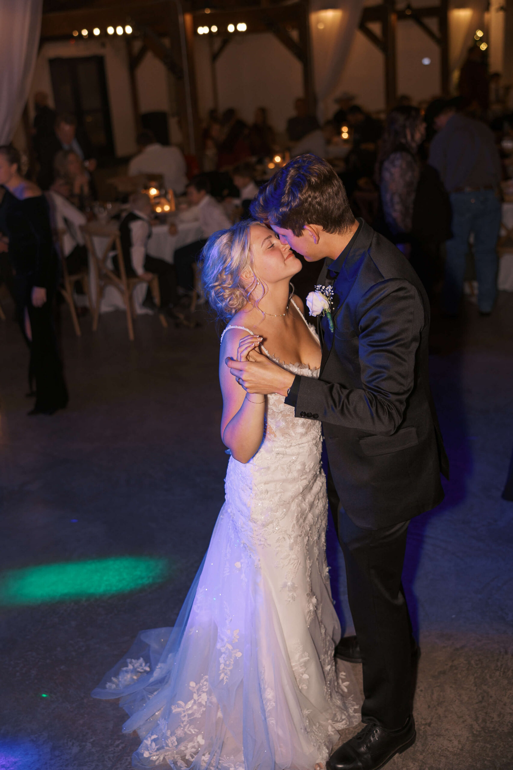 Newlyweds lean in for a kiss while slow dancing on the dance floor during their reception