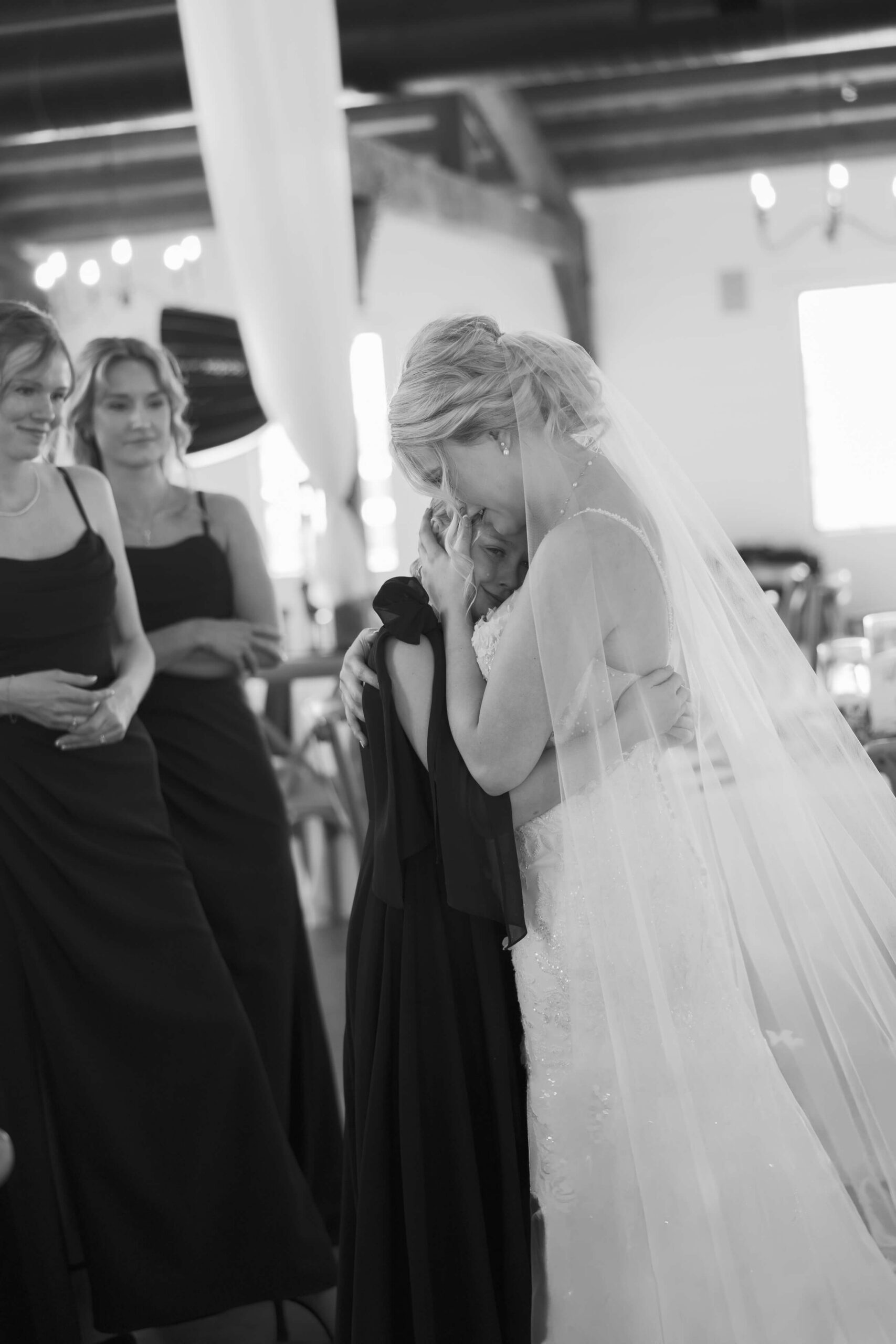 A bride cries and embraces a bridesmaid for a big hug