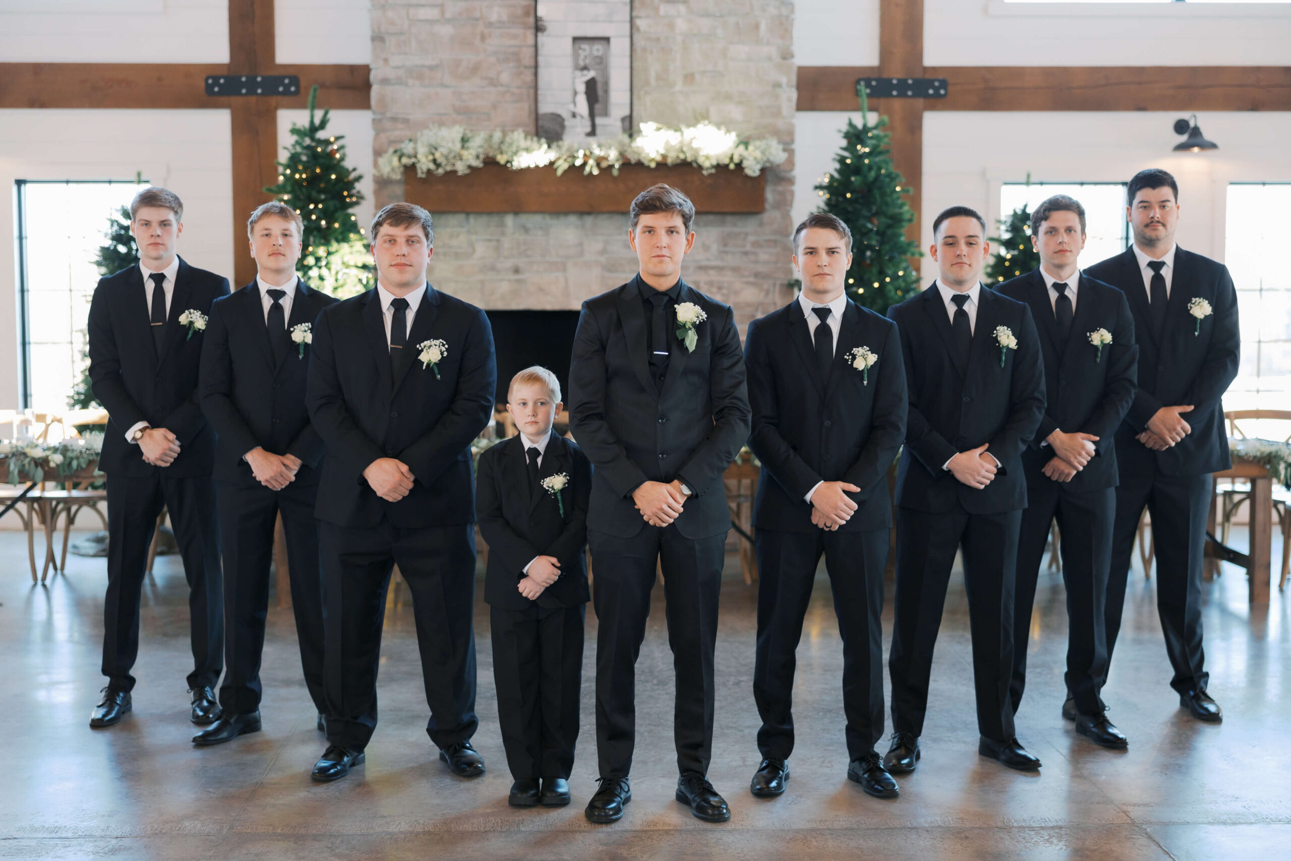 A groom stands with his groomsmen with hands crossed in front of them in black suits
