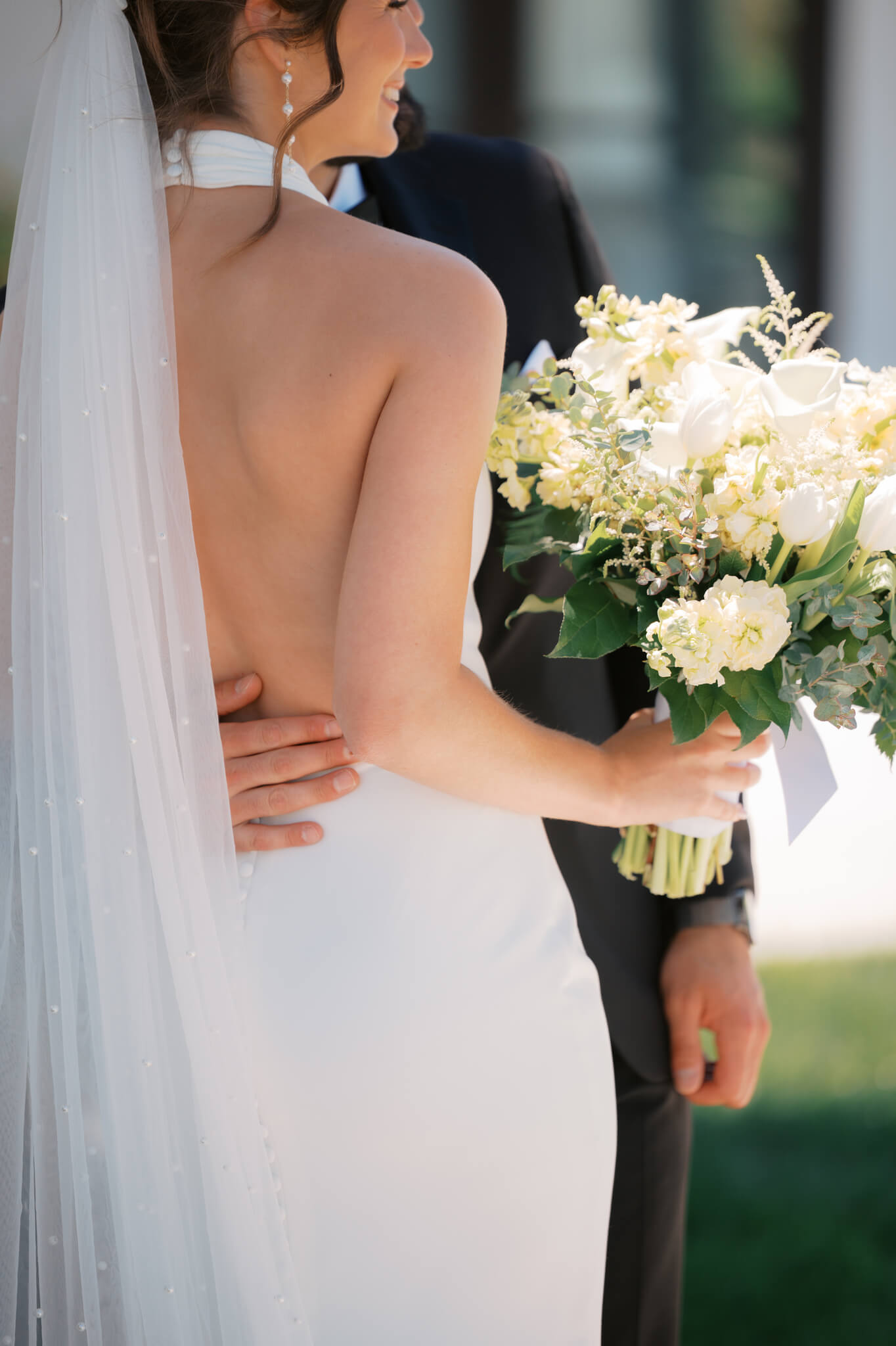 Details of a bride holding her white bouquet and smiling
