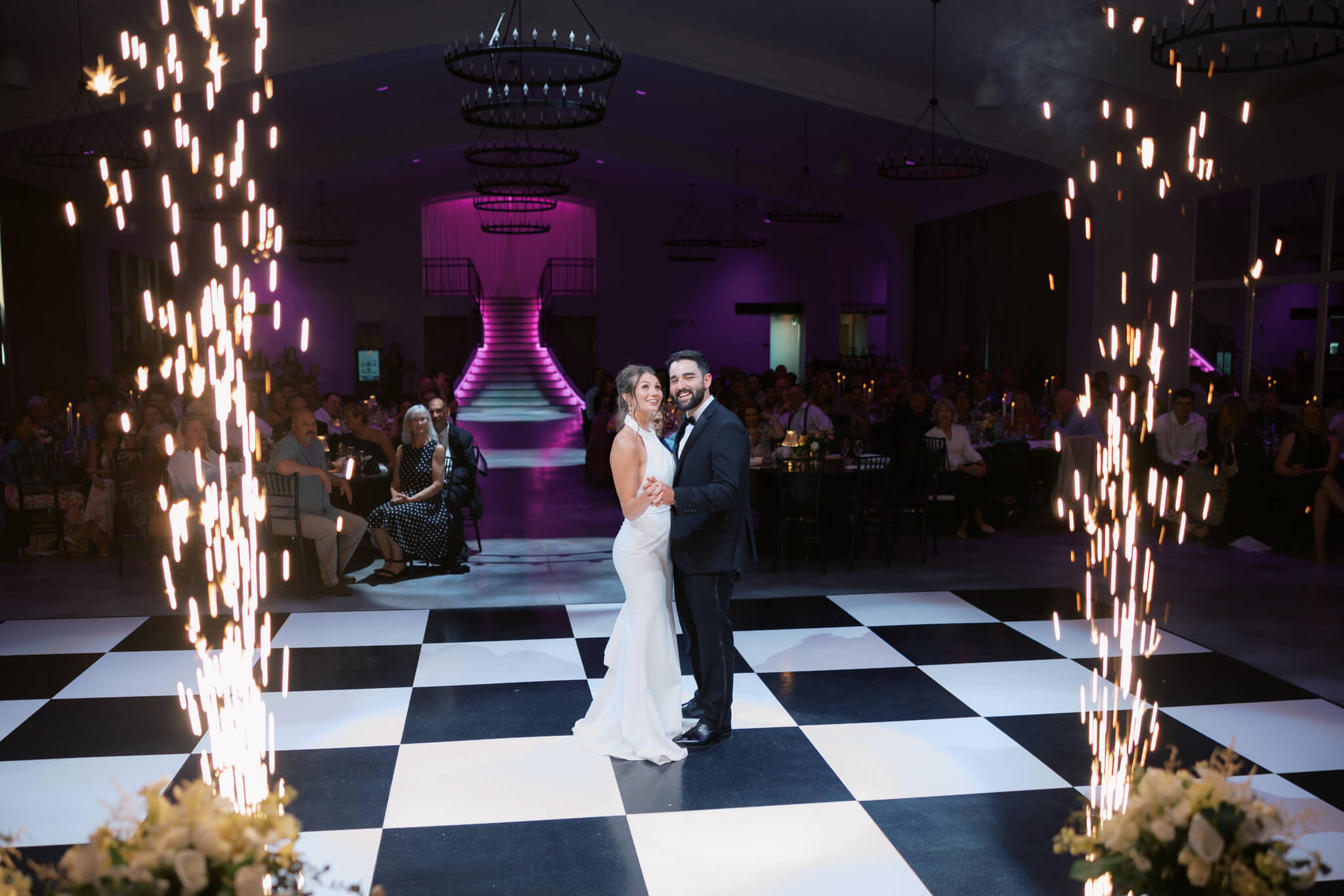 Newlyweds dance alone framed in sparklers and pink lighting at The Acreage wedding venue