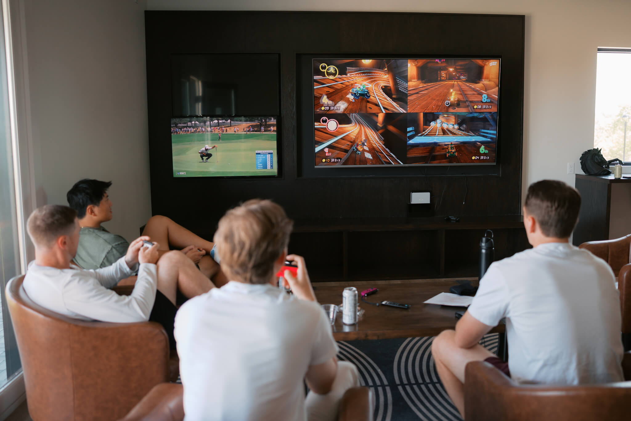A groom and his groomsmen sit in leather chairs playing video games before getting ready