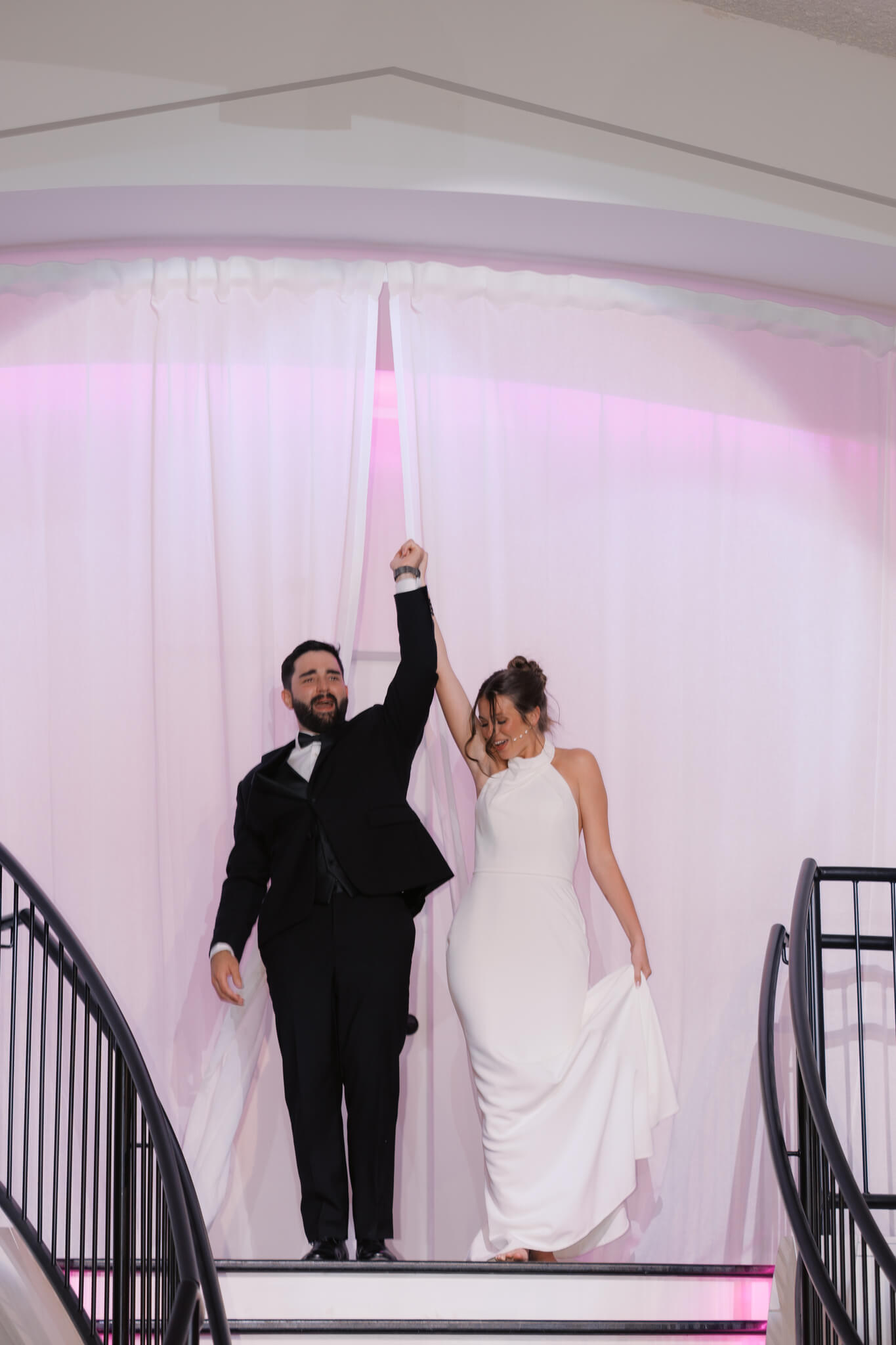 Newlyweds raise their arms in joy when entering their reception at The Acreage wedding venue