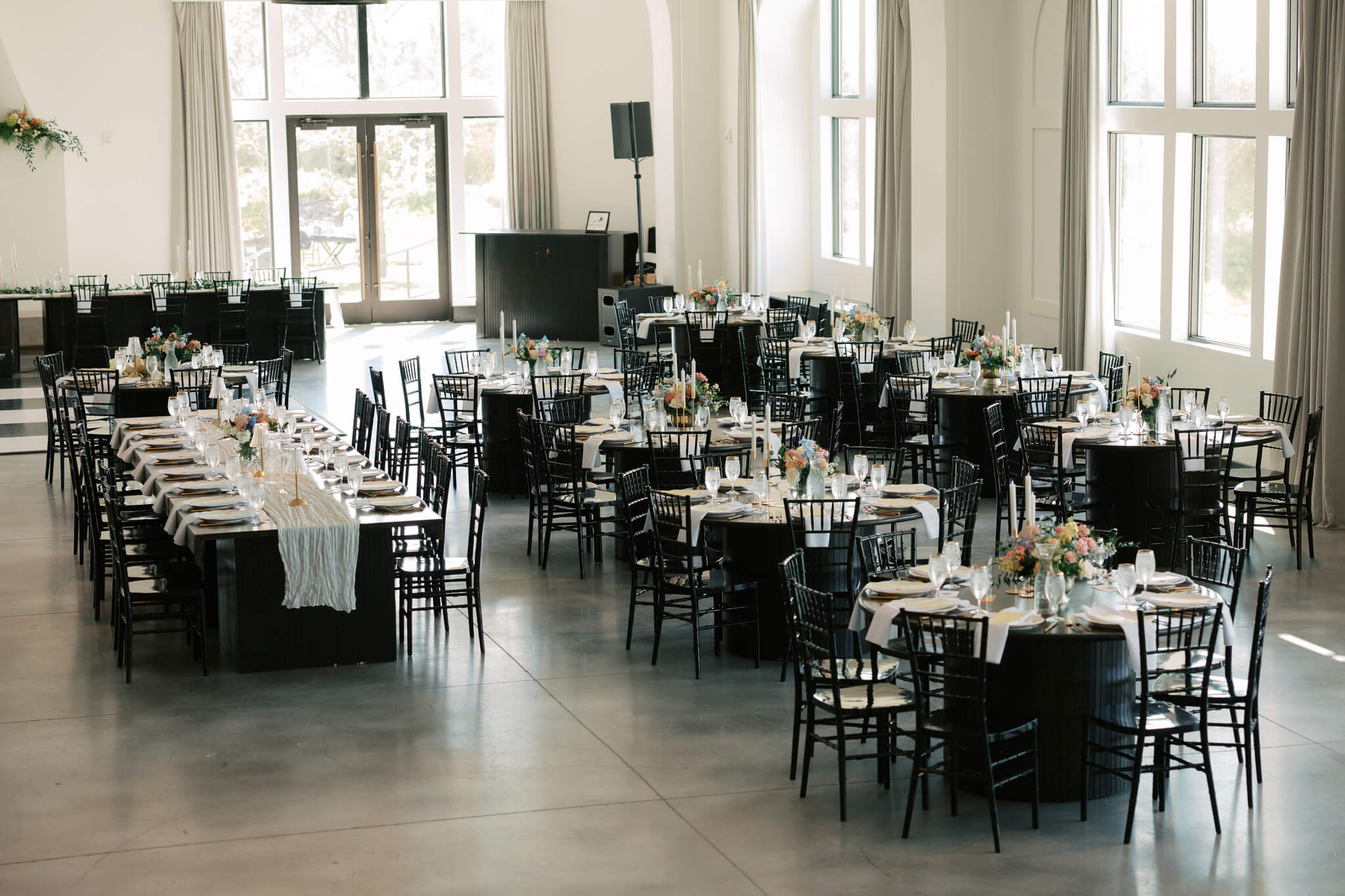 A look at a reception set up at The Acreage wedding venue with wooden tables and black chairs
