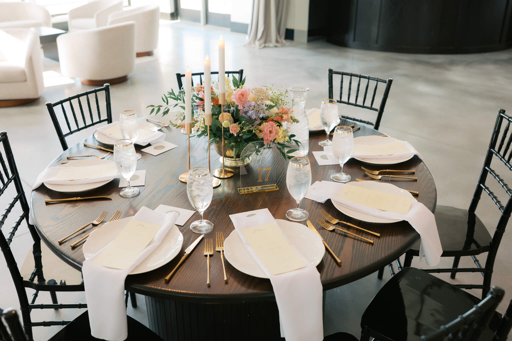 The Acreage wedding venue round reception table set up with white napkins, gold silverware and a colorful centerpiece