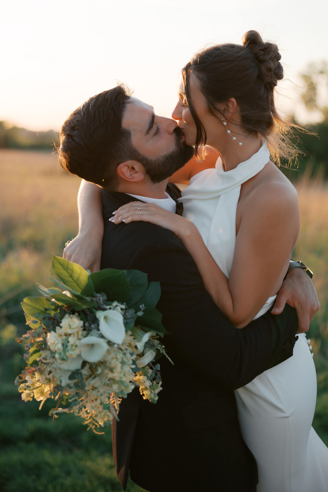 A couple at The Acreage wedding venue kiss at sunset in the tall grass