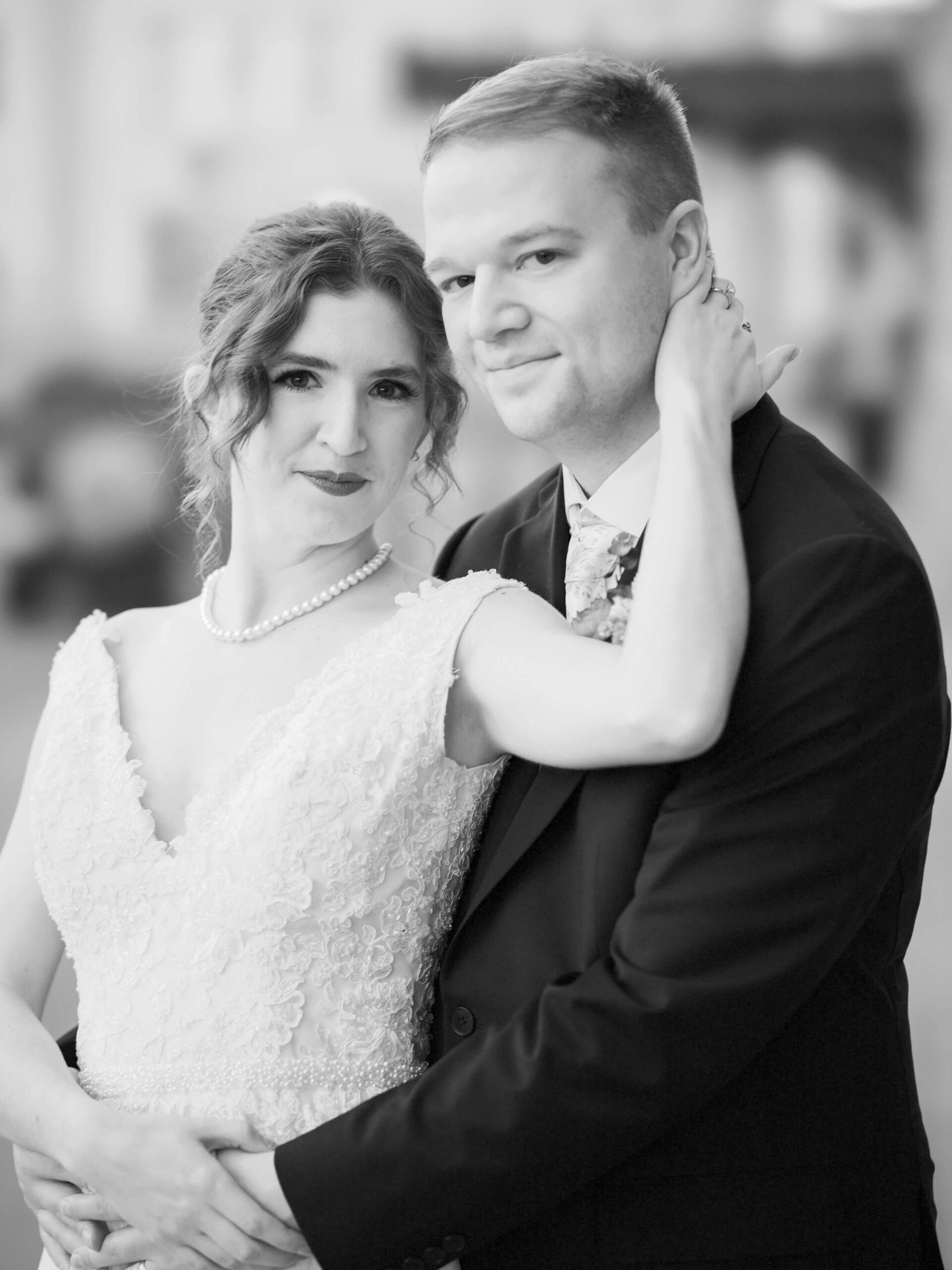 A bride smiles while leaning in to the chest of her happy husband