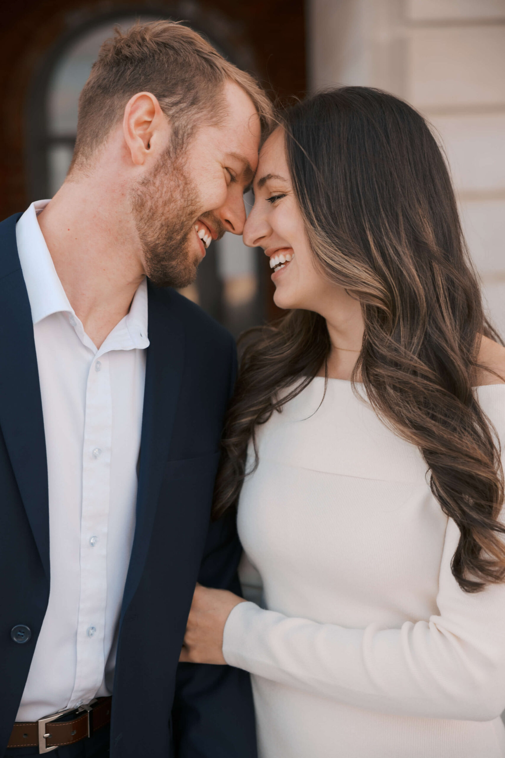 Newlyweds laugh while touching foreheads in white and blue