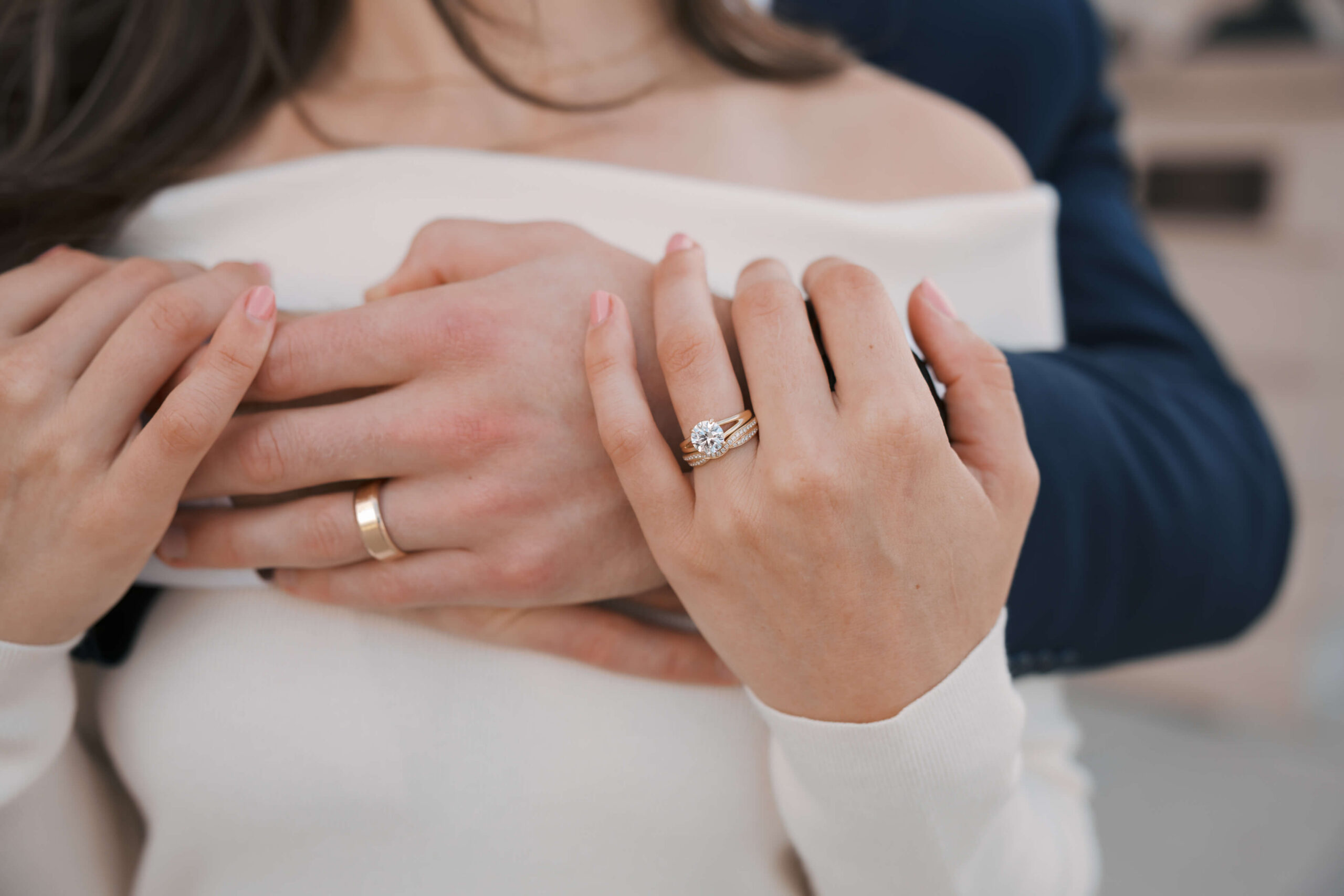 Details of a bride's ring hand on her groom's as they embrace during their joslyn art museum wedding