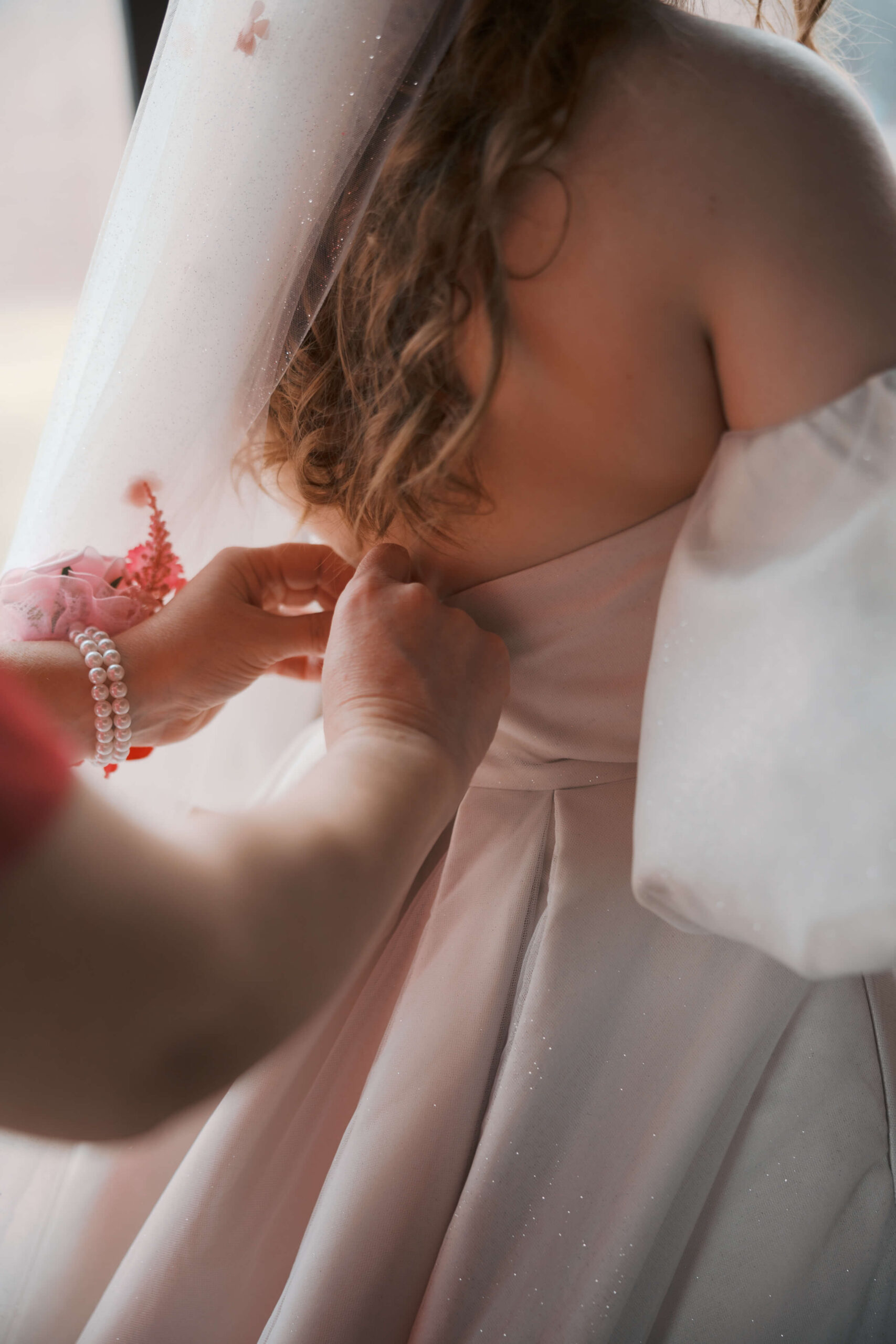 Details of mom helping button the wedding dress at zenia omaha