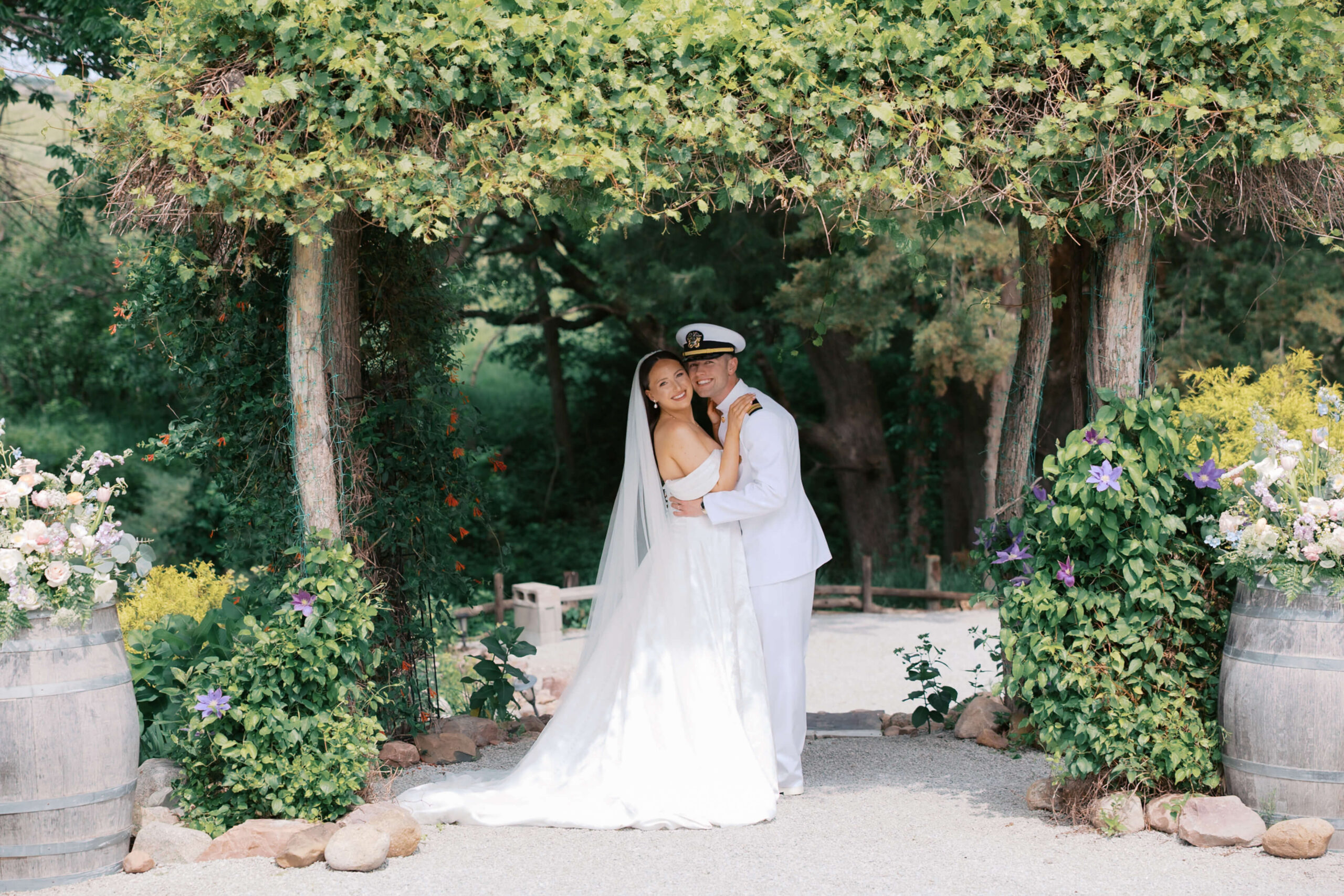 Newly married military couple smile cheek to cheek under a vine covered pergola at one of the lincoln wedding venues gardens