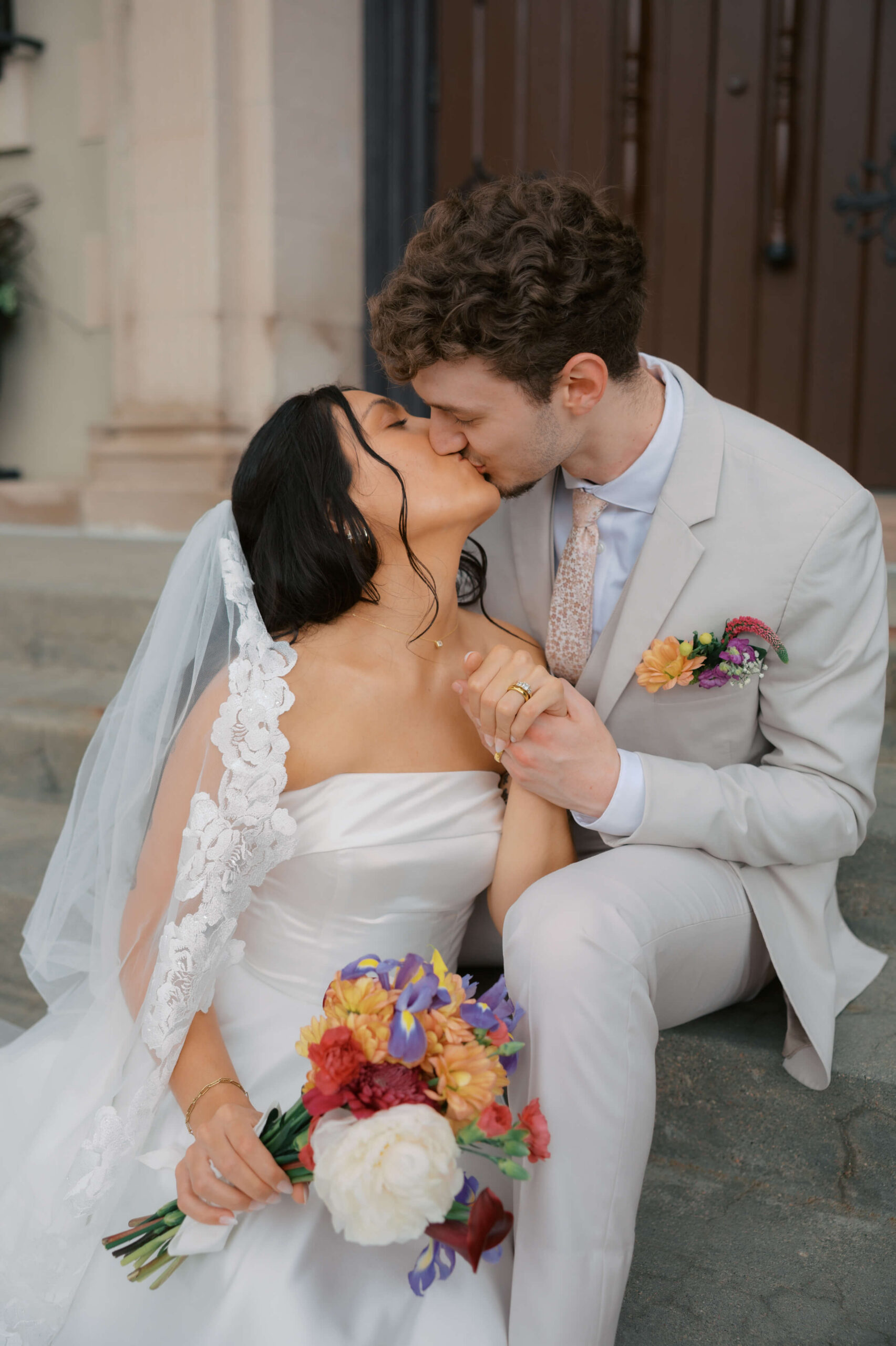 Newlyweds kiss while snuggling on concrete steps of one of the lincoln wedding venues