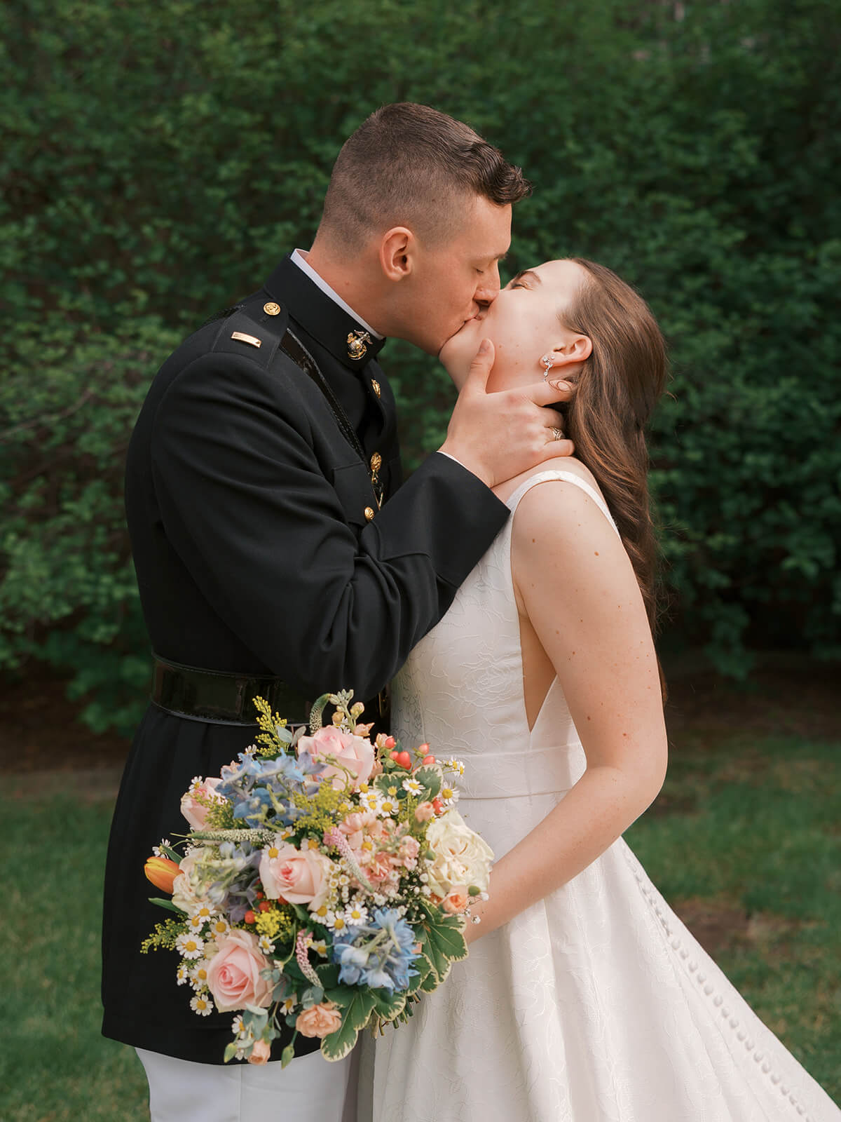 A US Marine kisses his bride during their wedding day in a garden