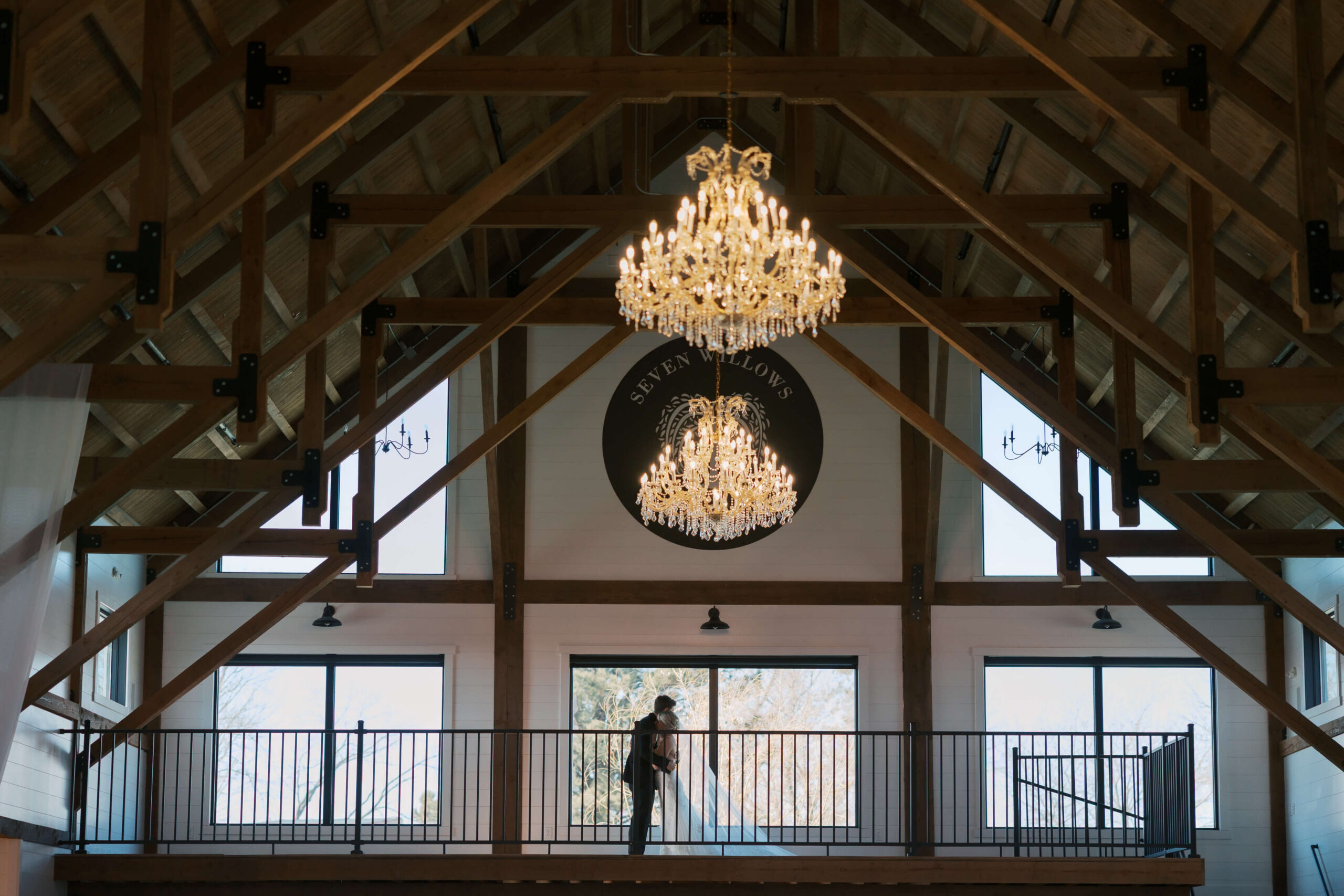 Newlyweds embrace on an indoor balcony under crystal chandeliers at one of the lincoln wedding venues
