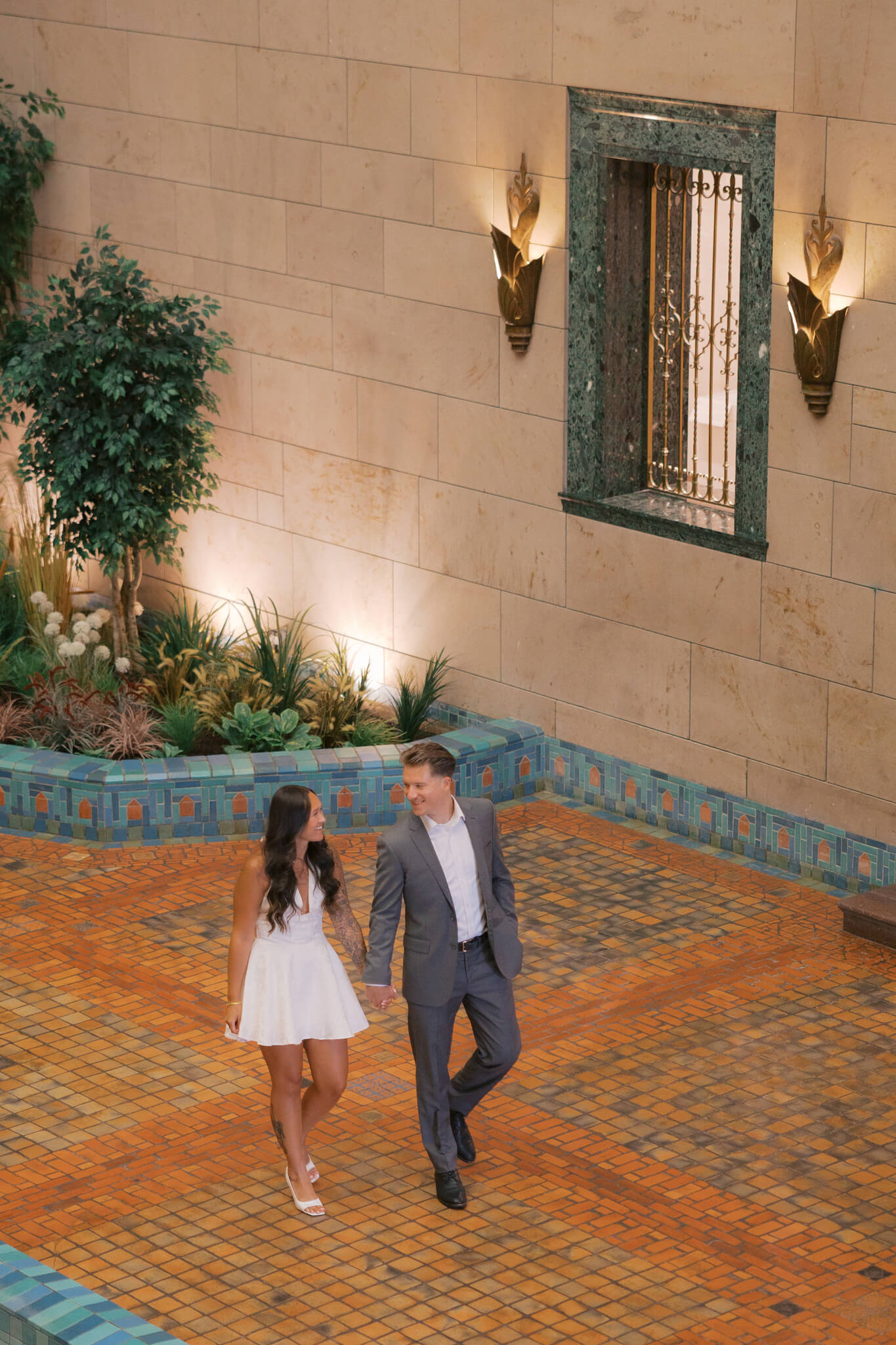 A happy couple walk the atrium holding hands