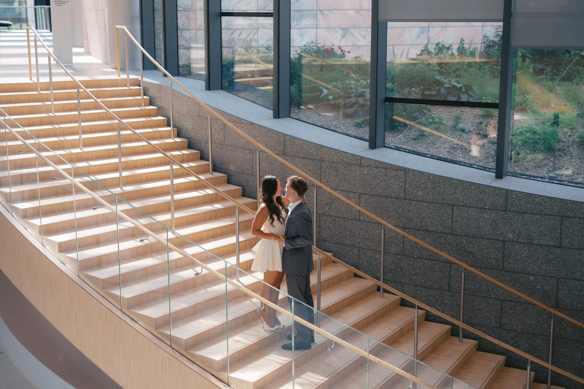 Happy newly engaged couple embrace on the stairs of the joslyn art museum wedding venue inside the lobby